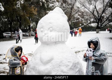 Wuhan, China. 07th Feb, 2022. Two girls play with the Beijing 2022 Winter Olympics mascot Bing Dwen Dwen, white, and Beijing Winter Paralympic mascot Shuey Rhon Rhon, red, in the Jiangtan park during a snowfall in Hubei.Wuhan ushered in the first snowfall of the Chinese new year. (Photo by Ren Yong/SOPA Images/Sipa USA) Credit: Sipa USA/Alamy Live News Stock Photo