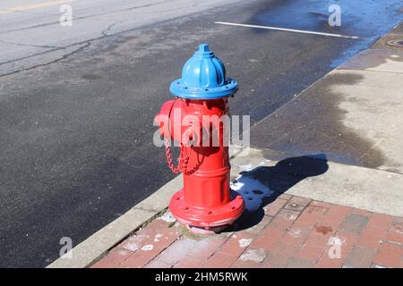 Red and blue fire hydrant on small town street Stock Photo