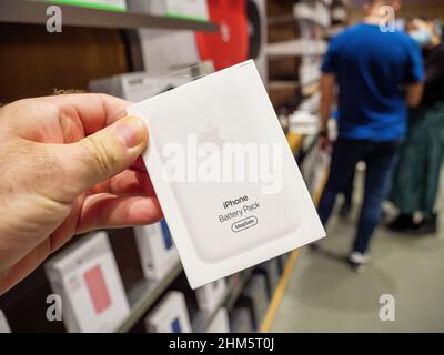 Paris, France - Sep 24, 2021: POV male hand holding new Apple Computers Battery Pack magnetic charger with customers defocused in background - accessory to charge wirelessly the iphone Stock Photo