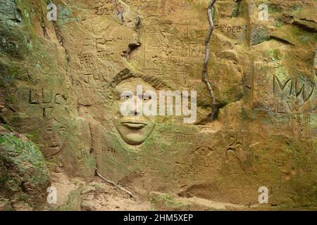 Face carving and other graffiti on the sandstone sides of a deep sunken holloway. Dorset, UK. Stock Photo