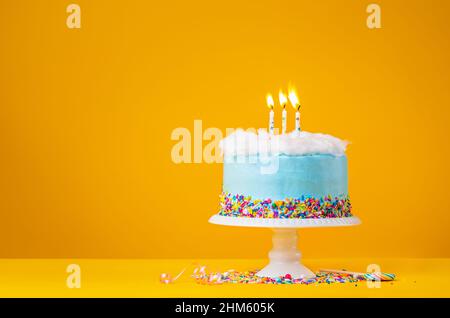 Blue Birthday Cake with three Candles over a yellow Background Stock Photo