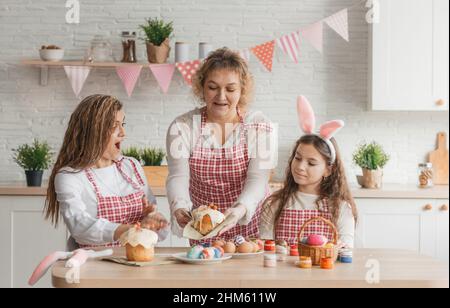 A caring, happy mother gives an Easter cake to her happy daughters. Stock Photo