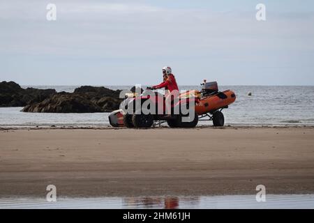 Lifeguard riding a RNLI quad bike on a beach in the UK Stock Photo