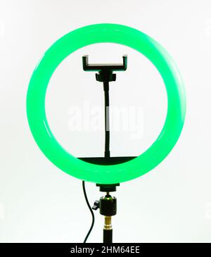 Modern tripod with ring light and smartphone on light blue background ...