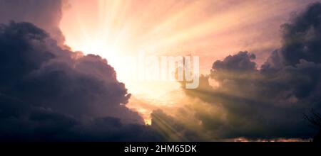 Cloudscape image of dark stormy clouds in blue sky with sun beam. The rays of the sun after the rain. Scenery with the sun's rays filtering through th Stock Photo