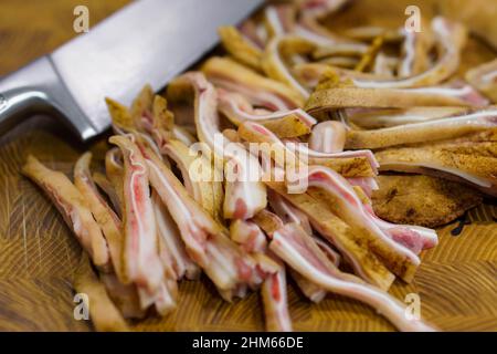 Selective focus on raw sliced ear of pork and chief knife on wooden desk. Asian cuisine menu Stock Photo