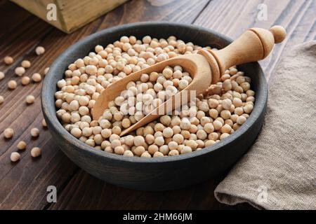 Raw chickpeas in bowl. Chickpeas in bowl and scoop on wooden table. Stock Photo