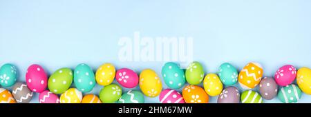 Colorful Easter Egg bottom border over a pastel blue paper banner background. Copy space. Stock Photo