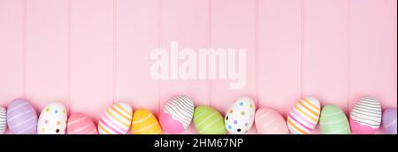 Colorful Easter Egg bottom border over a soft pink wood banner background. Top down view with copy space. Stock Photo