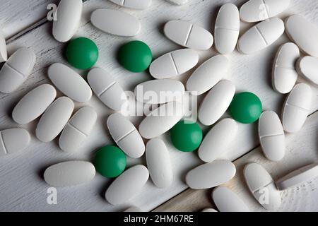 white and green pills on a wooden table top view Stock Photo