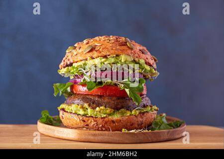 Portobello mushroom burger with red onion, tomato, arugula, avocado with sweet potato fries Stock Photo