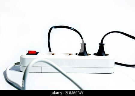 Extension cord with a red turned on button and inserted plugs and wires on a white background. Isolate. Copy space. Front view. Stock Photo