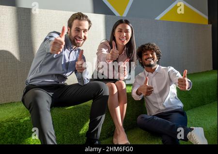 Group of young people feeling excited and cheerful in the lounge zone in the office Stock Photo