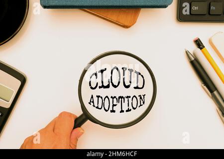 Hand writing sign Cloud Adoption. Conceptual photo strategic move by organisations of reducing cost and risk Office Supplies Over Desk With Keyboard Stock Photo