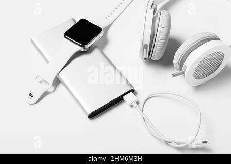 Modern power bank, smart watch and headphones on white background, closeup Stock Photo