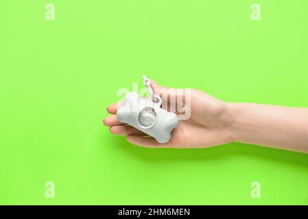 Woman holding dispenser with pet waste bags on green background, closeup Stock Photo