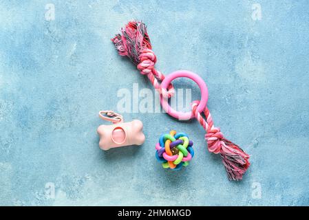 Dispenser with pet waste bags and toys on blue background Stock Photo