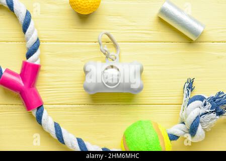 Dispenser with pet waste bags and toys on color wooden background, closeup Stock Photo