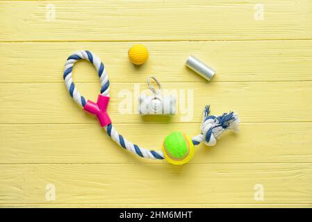 Dispenser with pet waste bags and toys on color wooden background Stock Photo