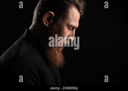 Calm young bearded man on black background Stock Photo