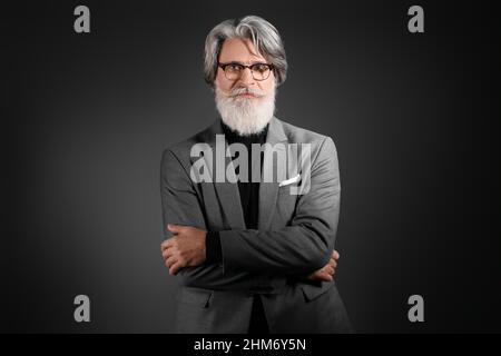 Portrait of handsome mature bearded businessman on dark background Stock Photo