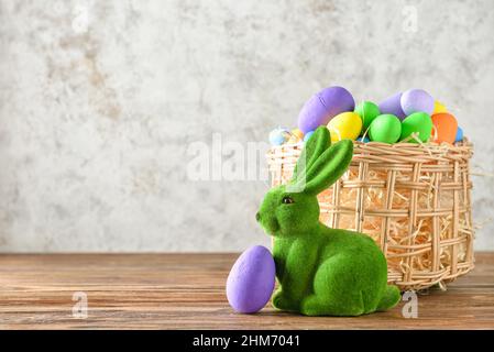 Easter bunny and wicker basket with painted eggs on grunge background Stock Photo