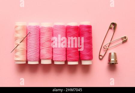 Multicolored thread spools, safety pins and thimble on color background Stock Photo