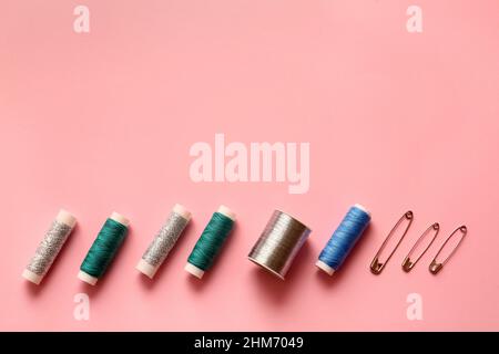 Different thread spools and safety pins on color background Stock Photo