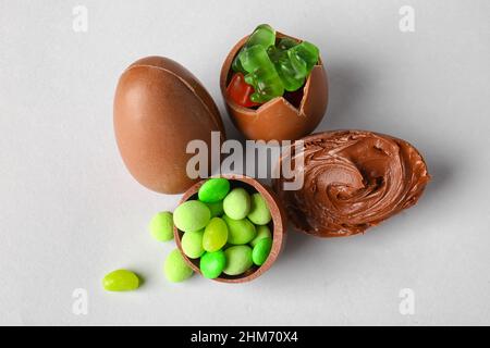 Delicious Easter eggs with candies and chocolate paste on light background Stock Photo