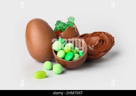 Delicious Easter eggs with candies and chocolate paste on light background Stock Photo