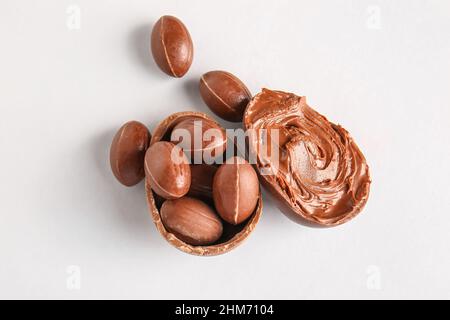 Different delicious Easter eggs with chocolate paste on light background Stock Photo