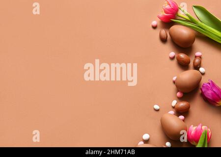 Composition with chocolate Easter eggs and flowers on color background Stock Photo