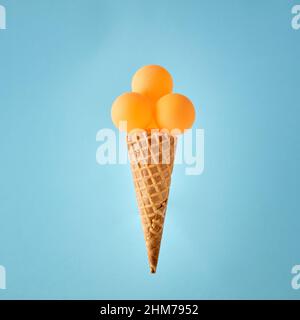 Yellow table tennis balls on ice cream cone against blue background. Concept of fitness, exercise, proper nutrition and sports. Stock Photo