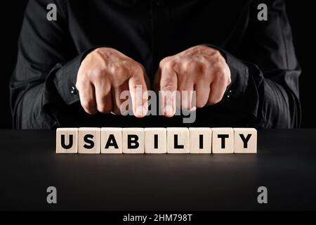 Male hands pointing to the word usability on wooden blocks. User experience quality or satisfaction concept. Stock Photo