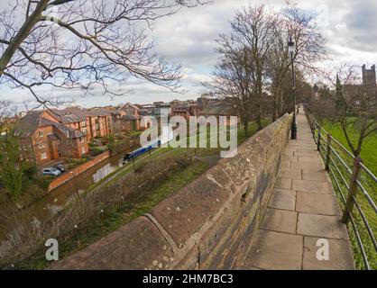 View of narrowboat from city walls moored in English urban scenery on British canal with luxury waterfront real estate property Stock Photo