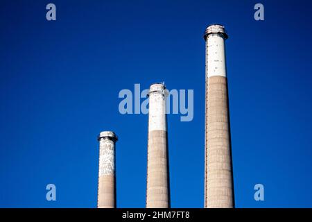Factory smokestacks against a blue sky Stock Photo