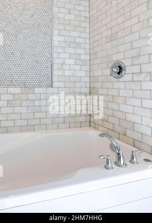 Vertical Alcove bathtub with marble subway tile surround and shower head Stock Photo
