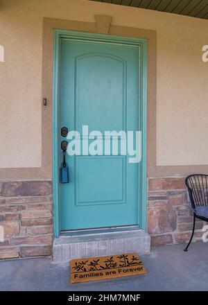Vertical Front porch exterior with mint green door and decorative doormat Stock Photo