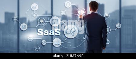SaaS Software as a Service concept with man hand pressing text. Stock Photo