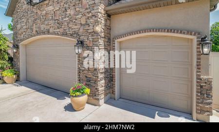 Panorama White puffy clouds Double arched sectional garage doors with potted plants outside Stock Photo