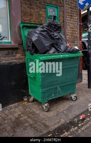 A bin with overflowing green rubbish bags Stock Photo