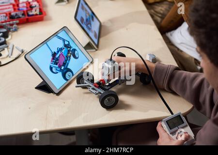 Close up of teenage boy building robot in engineering class at modern school and using digital tablet for programming, copy space Stock Photo