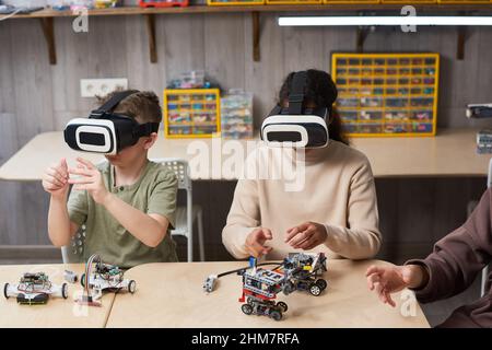 Portrait of two children wearing VR gear while building robots in engineering class at school Stock Photo