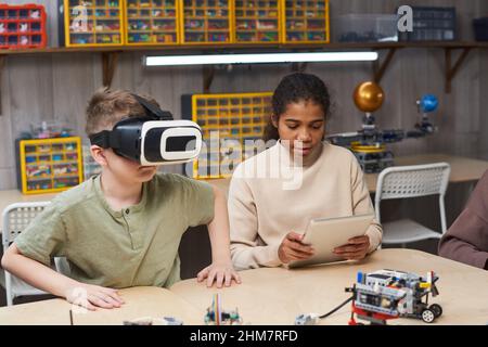 Team of two children building robot together and using VR gear while enjoying engineering class at school Stock Photo