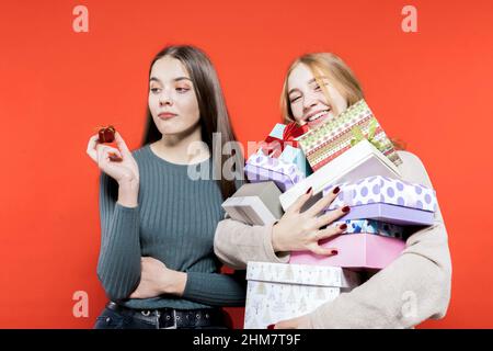 Surprise for christmas. Gift exchange. Girlfriends. Two pretty girls are holding many gift boxes in their hands. Two sisters. Friends. Stock Photo
