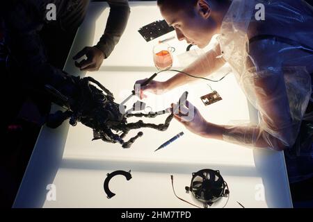 High angle view of woman engineering the cyberpunk arm connected with human body at the table Stock Photo