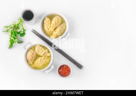 Dumplings are served in white cups with sauces on a serving board . Top view. Copy space. Stock Photo