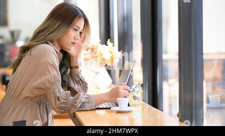 Concentrated businesswoman or university student working, using digital tablet touchpad computer in the cafe. Female remote working concept. Stock Photo