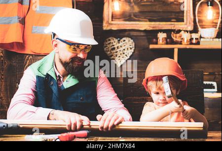 Father and son hammers nails with a hammer in a wooden board. Happy fatherhood. Stock Photo