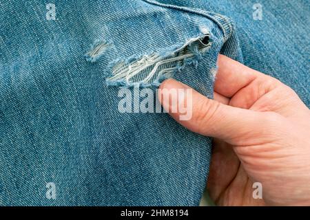 Person exploring hole in ripped jeans before sew up it Stock Photo
